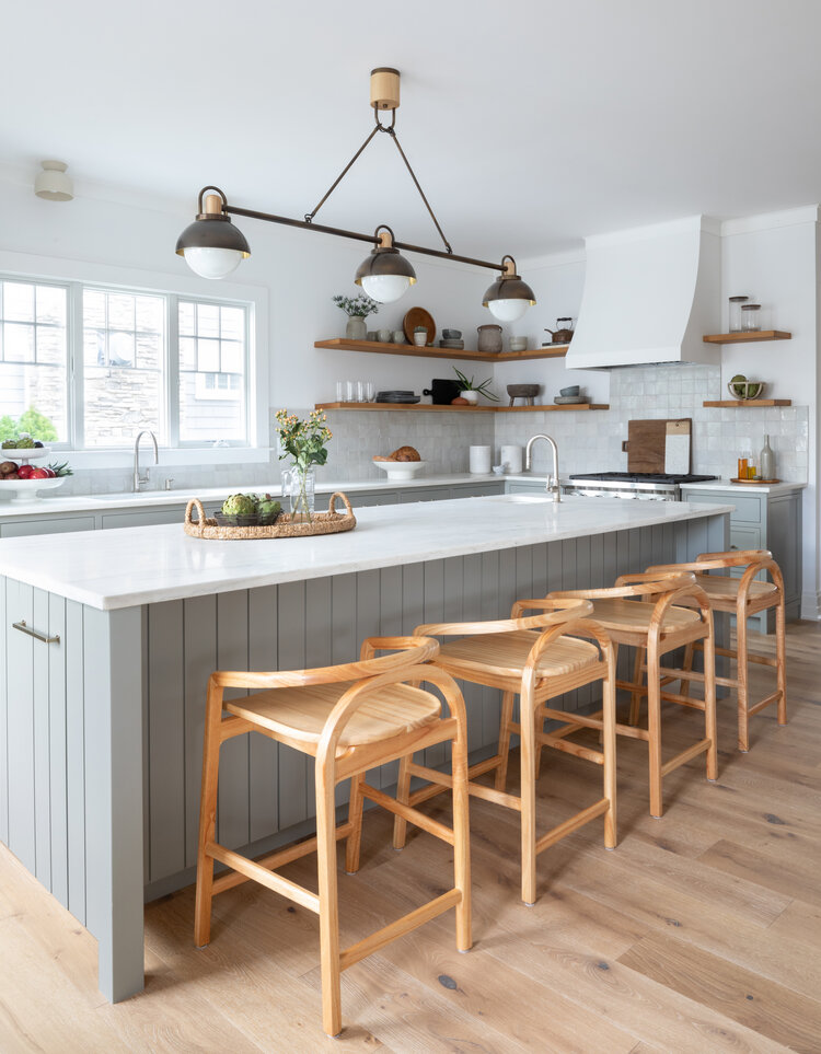 A fresh modern kitchen design with vertical shiplap on the kitchen island, bent wood counter stools, and linear lighting over the island.  kitchen makeover - organic modern decor - kitchen island ideas - organic modern kitchen - kitchen lighting