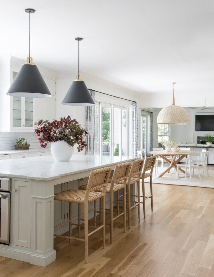 Love this beautiful open concept kitchen, dining, and living room with modern black cone pendant lights over the island and woven counter stools - modern kitchen design - kitchen island ideas - kitchen lighting - great room