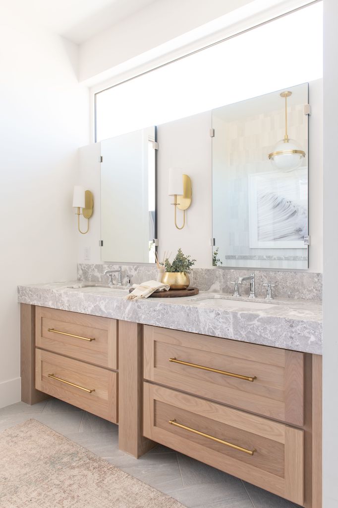 A stylish master bathroom design featuring a light wood vanity paired with polished nickel faucets and brass lighting and cabinet pulls - modern bathroom ideas - bathroom decor - bathroom vanity - bathroom cabinet ideas - bathroom lighting - becki owens