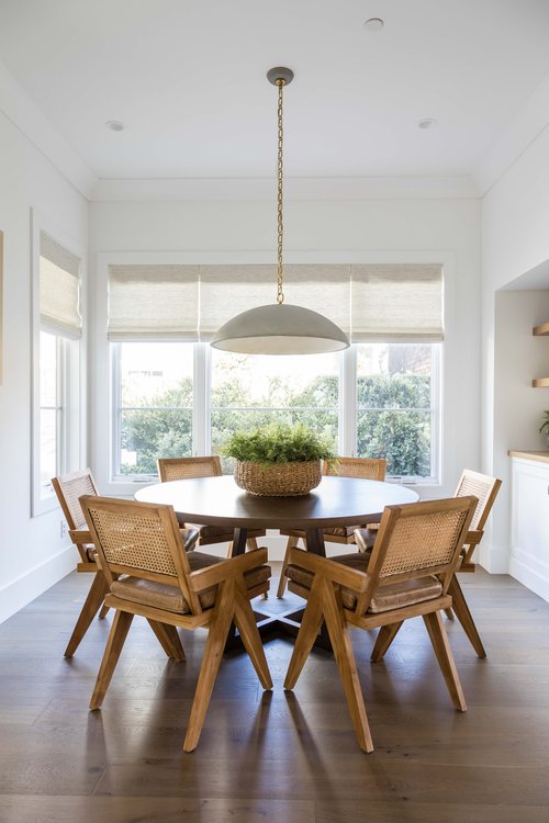 I love this stylish kitchen dining area with a round table, cane dining chairs, and a concrete chandelier - dining room ideas - coastal dining room - pure salt