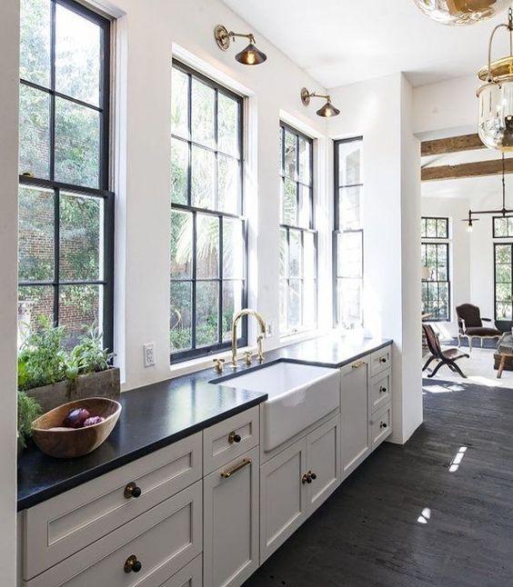 Love this beautiful kitchen design with white cabinets, black countertops, brass sconces, and black framed windows - kitchen cabinet ideas - kitchen lighting - room decor - jen langston