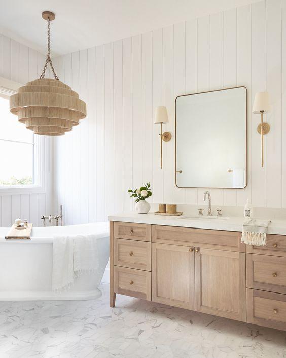 Love this beautiful bathroom design featuring a light wood vanity, brass sconces and pulls, a corner tub, vertical shiplap walls, and woven pendant light over the tub - michelle d young design - bathroom remodel - bathroom decor - bathroom ideas - organic modern bathroom