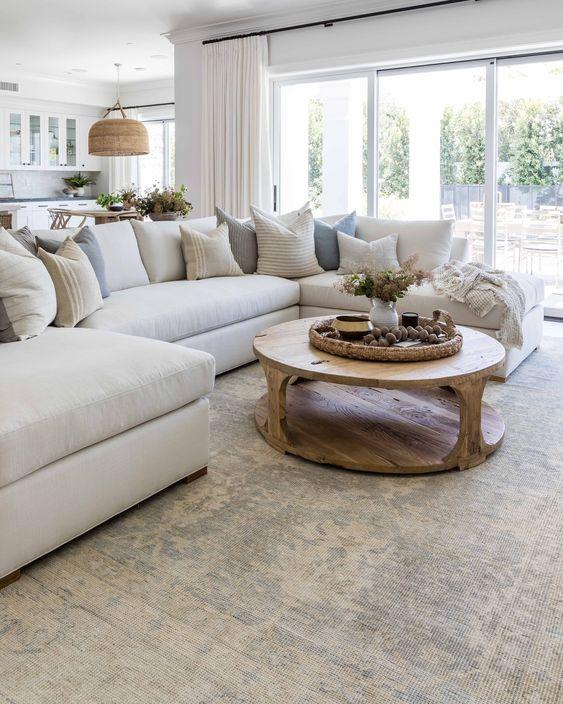 Love this beautiful living room design with a large sectional, round wood coffee table, and neutral furniture and decor - living room ideas - living room decor - coastal interiors - modern coastal living room ideas - pure salt