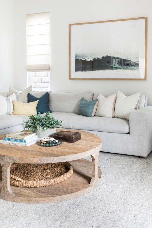 Love this beautiful modern living room design with a large sectional, round wood coffee table, neutral decor and furniture, and modern coastal artwork - living room ideas - living room decor - living room furniture - living room table - coastal decor - coastal living room - organic modern decor - pure salt interiors