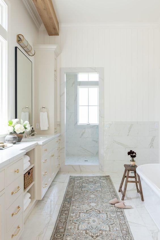 Love this beautiful bathroom design with a light oak vanity cabinet, wooden beam, marble countertops and shower enclosure, freestanding tub, and vintage Turkish inspired runner - modern bathroom design - mixing metals in the bathroom