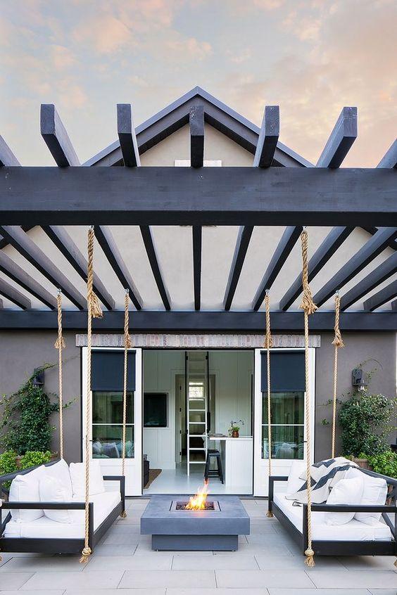 Gorgeous modern patio with black pergola, two swing beds, and a firepit in between - sherwin williams iron ore - patio ideas - patio decor - outdoor ideas - patio swings - outdoor swings - patio furniture ideas