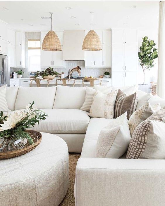 Love this beautiful modern living room design with a large sectional, round coffee table ottoman, and neutral decor and lighting - coastal living rooms - pure salt interiors