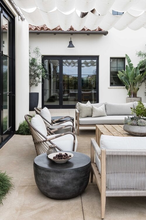 Gorgeous outdoor seating area and covered patio with modern furniture and outdoor fireplace - Pure Salt Interiors