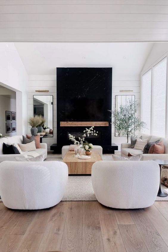Love this beautiful modern living room design with two curved chairs, vaulted ceilings, wood coffee table, fireplace, tv wall, tall windows and ceilings, neutral decor and furniture, and chandelier - living room furniture - living room decor - living room table - tv wall ideas -rh style - modern earthy living room - the hillary style
