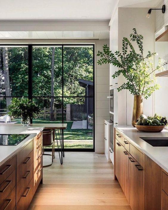 Любите этот современный дизайн кухни с кухонными шкафами из натурального дерева, белыми столешницами, окнами с черными рамами и зеленью - переделка кухни - идеи кухонного шкафа - современные идеи кухни - тенденции домашнего декора и стили дизайна 2023 года - архитекторы косилки болота