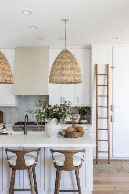 Love this beautiful modern coastal kitchen design with white kitchen cabinets, wood counter stools, and woven pendant lights over the kitchen island - pure salt interiors