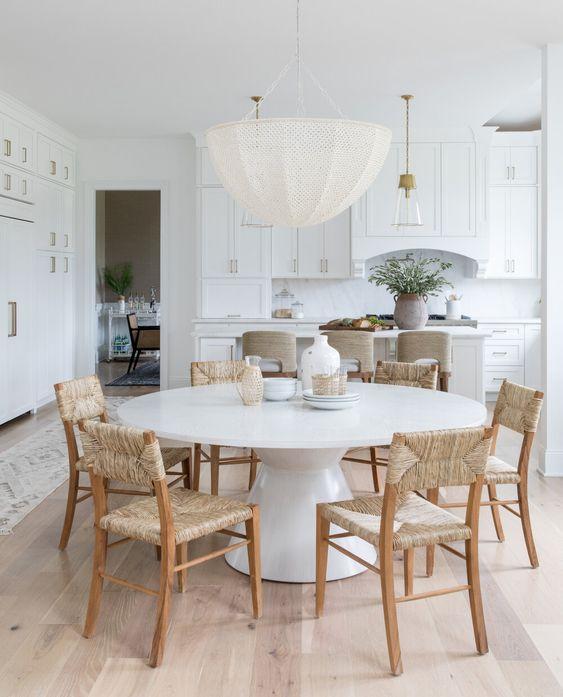 Love this beautiful modern dining room and kitchen with a round dining table, woven wood dining chairs, and a large woven chandelier - dining room ideas - dining room table - dining room lighting - coastal dining rooms - dining room furniture - kitchen dining - salt design