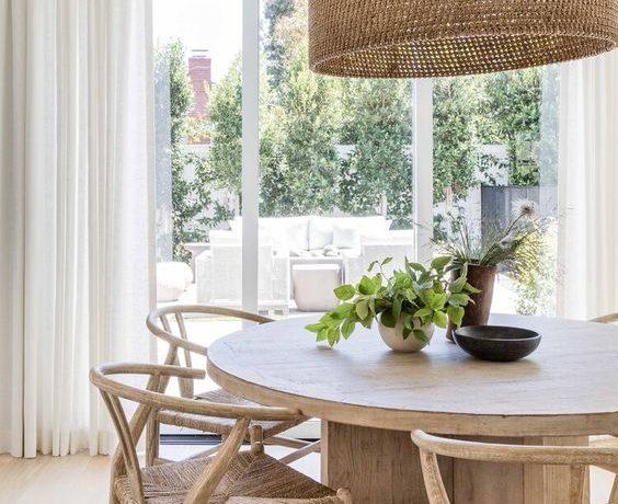 Love this beautiful modern dining room with a round wood dining table, wishbone style wood dining chairs, and a large woven pendant light
