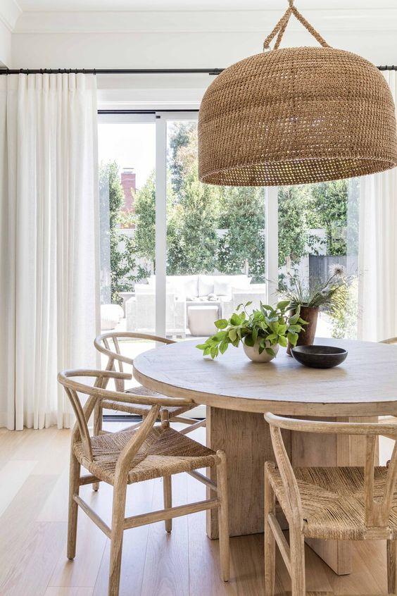 Love this beautiful modern dining room with a round wood dining table, wishbone style wood dining chairs, and a large woven pendant light