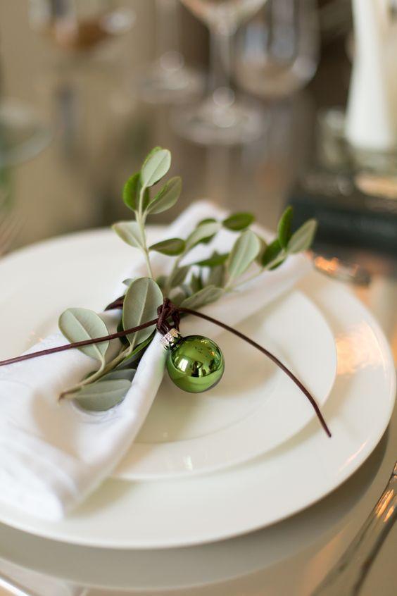 Love this simple Christmas table and place setting idea with a simple green ornament and fresh greenery sprig tied around each napkin - Christmas table setting ideas - Christmas decor - Christmas table ideas