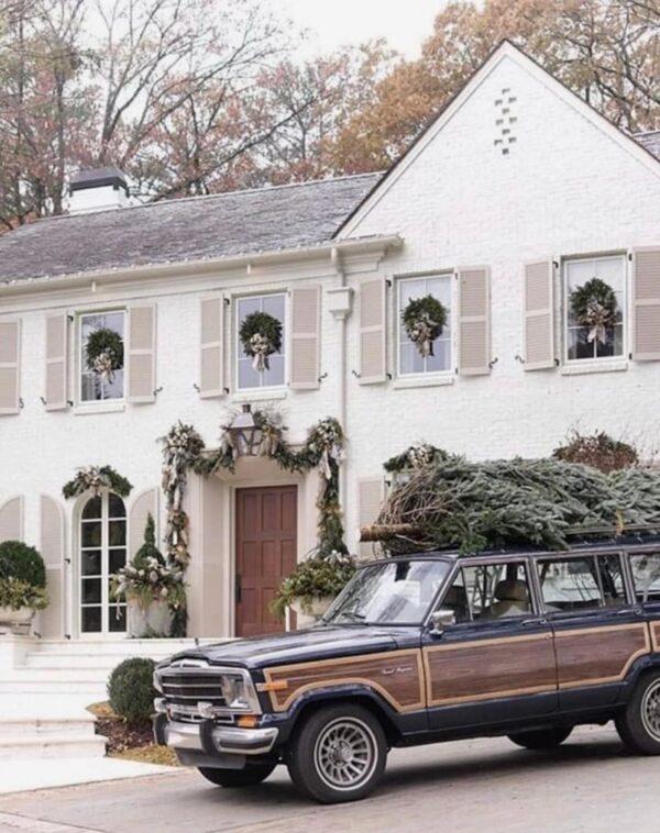 Love this beautiful Christmas home decorated for the holidays with wreaths on the windows, garlands, and a fresh Christmas tree on top of the Wagoneer - pure Christmas charm - atlanta homes and lifestyles