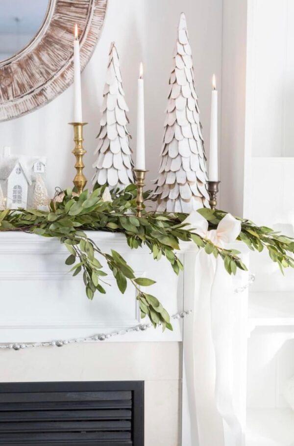 Love this beautiful Christmas mantel display, featuring fresh greenery, brass candlesticks, and white trees and tiny houses - craftberry bush
