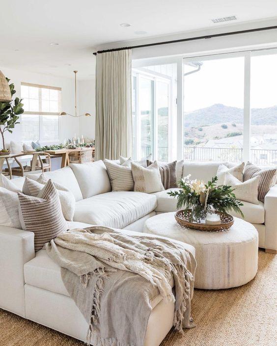 Beautiful modern living room with large white sectional, neutral decor, and round ottoman coffee table - living room furniture - living room table - living room design - open concept living room ideas - pure salt interiors