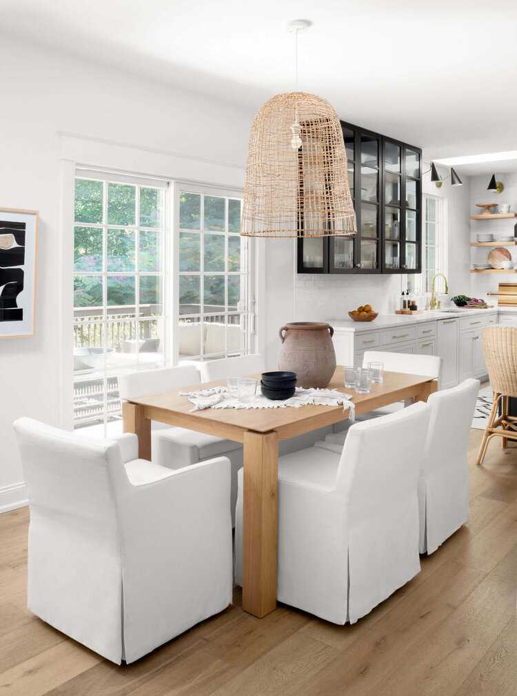 Love this beautiful modern kitchen dining area with slipcovered chairs and an airy woven pendant light over the wood dining table - kitchen ideas - kitchen dining - beach house decor - dining furniture