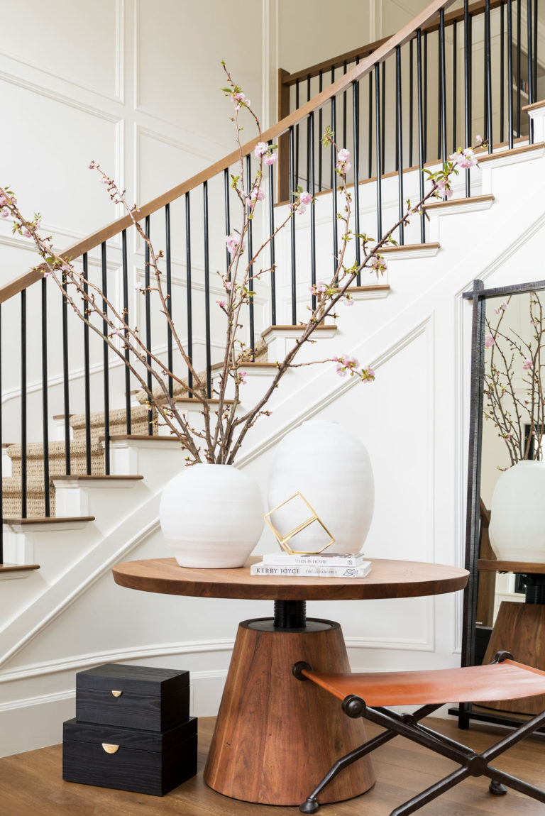 Love this beautiful entryway with a curved staircase, round wood foyer table, and leather stool - studio mcgee