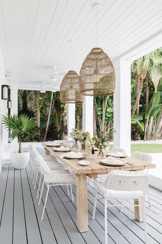 Love this beautiful covered porch and outdoor living and dining area with a wood dining table, white dining chairs, and woven pendant lights - patio decorating ideas - outdoor ideas - calimia home