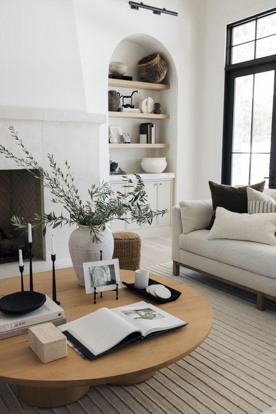 Love this beautiful organic modern living room design with a fireplace, built-in shelving, and a round wood coffee table - the life styled co.