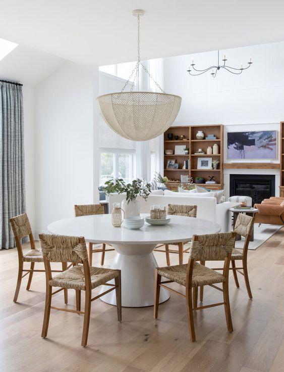 Love this beautiful modern dining area and living room with a round dining table, woven dining chairs and a statement chandelier - open concept home - dining room ideas - coastal style