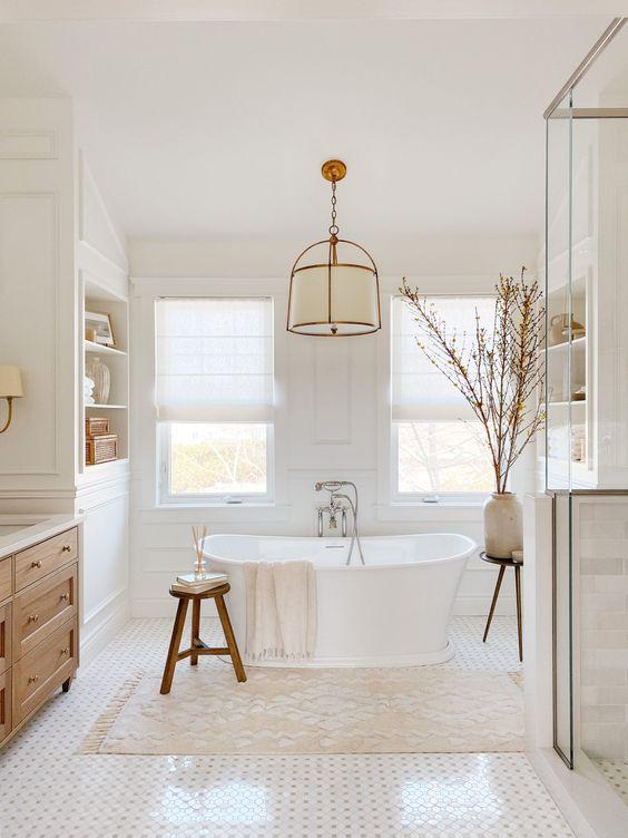 Love this beautiful bathroom design with a light wood vanity, free-standing tub, and light neutral decor - akb design studio