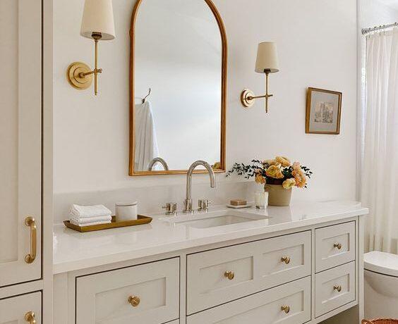 Love this beautiful timeless bathroom design with a curved wall mirror and brass sconces - akb design studio