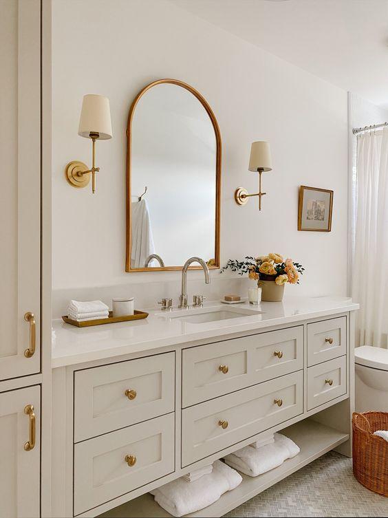 Love this beautiful timeless bathroom design with a curved wall mirror and brass sconces - akb design studio