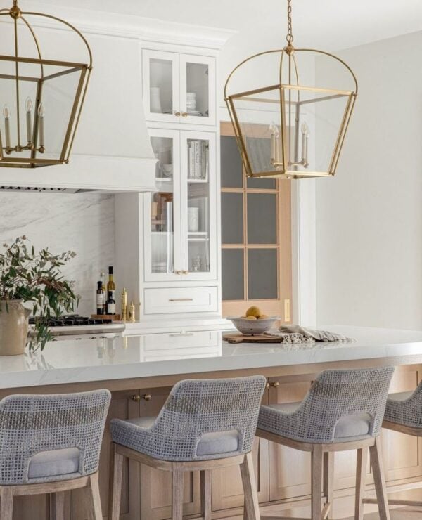 Love this beautiful modern coastal kitchen design with brass lantern pendant lighting, warm white cabinets, and woven counter stools - Shannon Weller Design