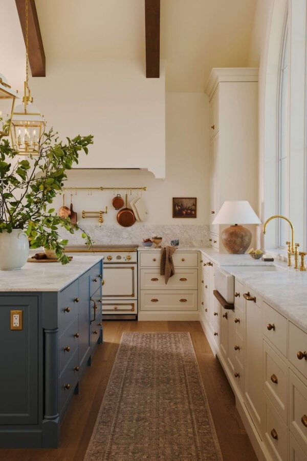 Luxury warm white kitchen with large island, quartz countertops, and pendant lighting.
