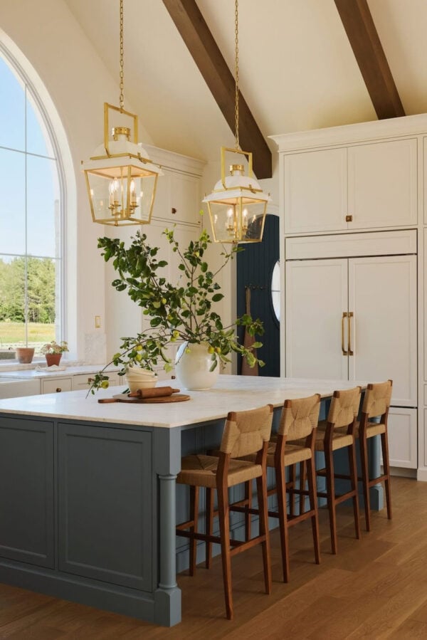 Beautiful timeless warm white kitchen with blue island and wooden beams - akb design studio