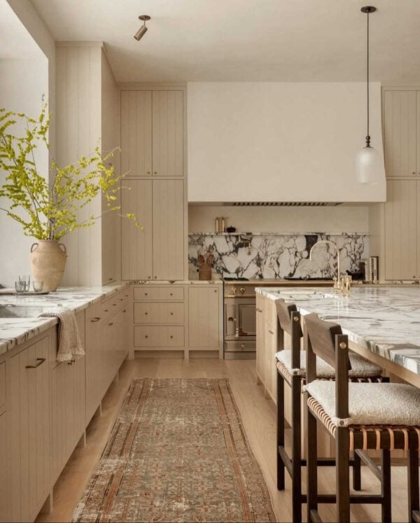 Modern kitchen with marble slab backsplash, concealed appliances, and quartz countertops.