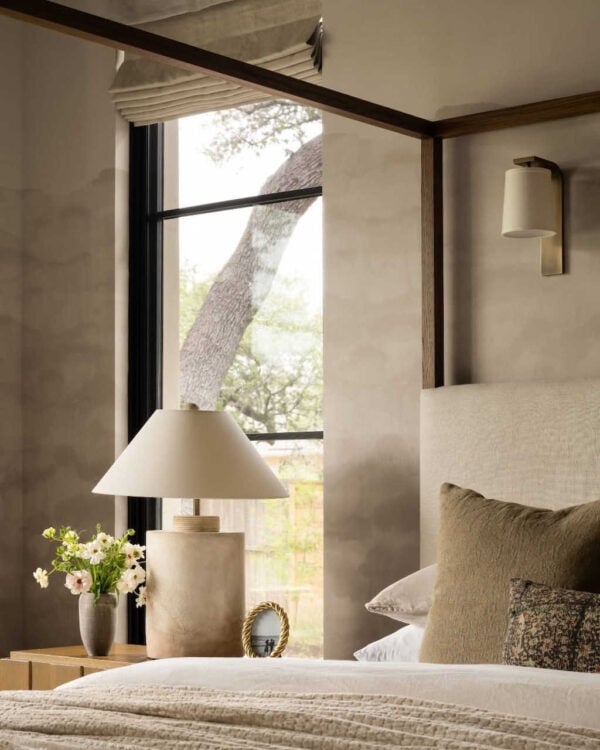 Neutral bedroom with plaster-textured wall, layered linen bedding, and soft organic forms.