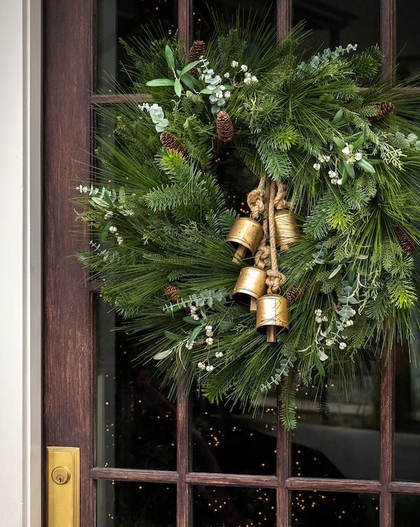 Love this beautiful front door Christmas wreath with brass bells and a mix of evergreen boughs and stems - studio mcgee