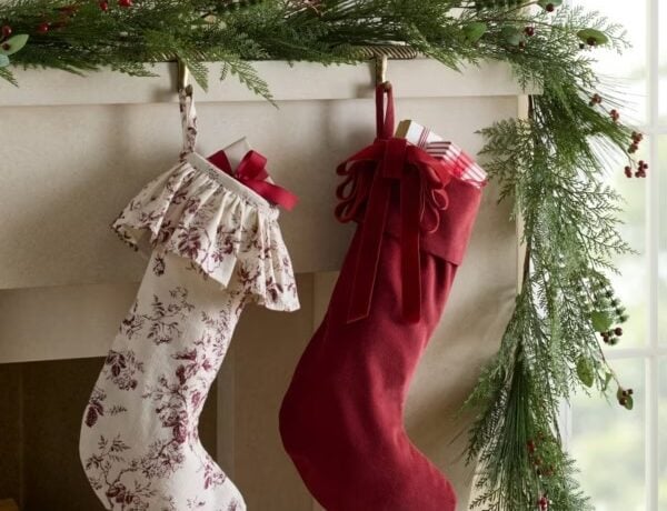 Christmas mantel decorated with two red and white stockings and an evergreen garland