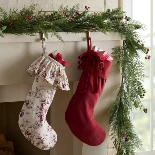 Christmas mantel decorated with two red and white stockings and an evergreen garland