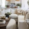 Love this beautiful modern living room design with a large sectional, round coffee table ottoman, and neutral decor and lighting - coastal living rooms - pure salt interiors