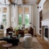 Light-filled living room featuring a curved sofa and warm ambient lighting from brass sconces, showcasing 2026 home décor trends and color palette